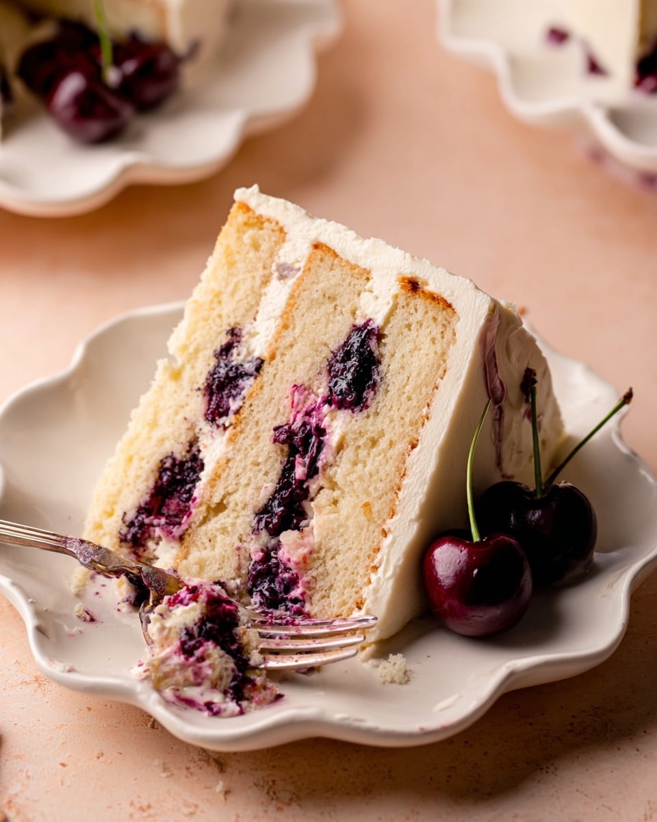 A slice of three-layer light yellow cake sits on a white scalloped plate, each layer separated by thick, dark purple and red cherry filling that looks juicy and slightly glossy. The top of the cake is covered with smooth, creamy off-white frosting, and two whole dark cherries with stems rest on the side of the slice. A silver fork with bits of cake and cherry filling is placed near the bottom edge of the plate, all set against a white marbled textured surface. photo taken with an iphone --ar 4:5 --v 7