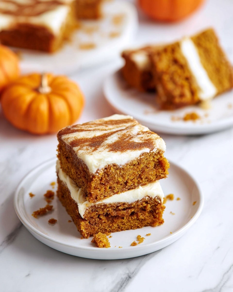 Two square pieces of pumpkin cake are stacked on a white plate, each with two layers of soft, moist orange-brown cake and a creamy white swirl layer in the middle, with some crumbs scattered around. In the background, there is another white plate with a similar cake piece partly eaten. Small orange pumpkins sit nearby on a white marbled surface, adding a warm fall touch. Photo taken with an iphone --ar 4:5 --v 7
