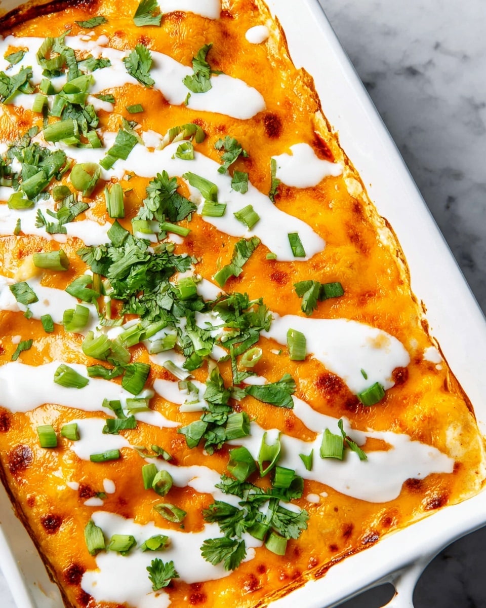 A white baking dish holds a creamy orange baked casserole with a smooth melted cheese layer on top that has slightly browned edges. White sauce is drizzled across the surface in wide, uneven lines. Chopped fresh green onions and bright green cilantro leaves are scattered evenly over the sauce, adding a fresh pop of color and texture. The dish is set against a white marbled textured surface. photo taken with an iphone --ar 4:5 --v 7