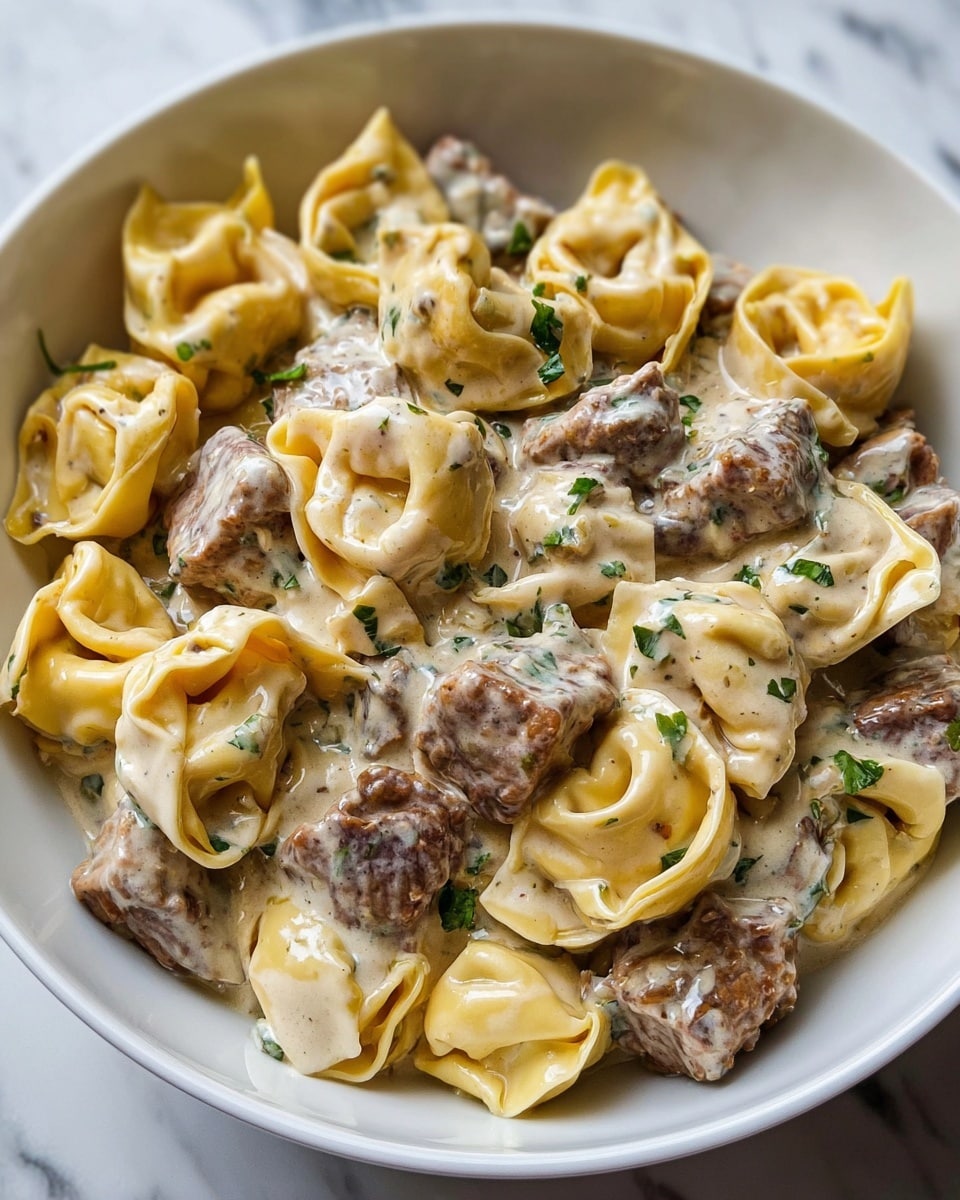 The image shows a close-up of creamy tortellini pasta covered in a thick white sauce with green herb flecks, all served in a white bowl. The tortellini are yellow and have a soft, folded shape, scattered evenly throughout the bowl. There are chunks of cooked brown meat mixed in the dish, coated with the sauce and sprinkled with small pieces of fresh green herbs. The texture of the sauce looks smooth and rich, clinging to the pasta and meat, with a few darker specks visible in it. The background surface is a white marbled texture. photo taken with an iphone --ar 4:5 --v 7