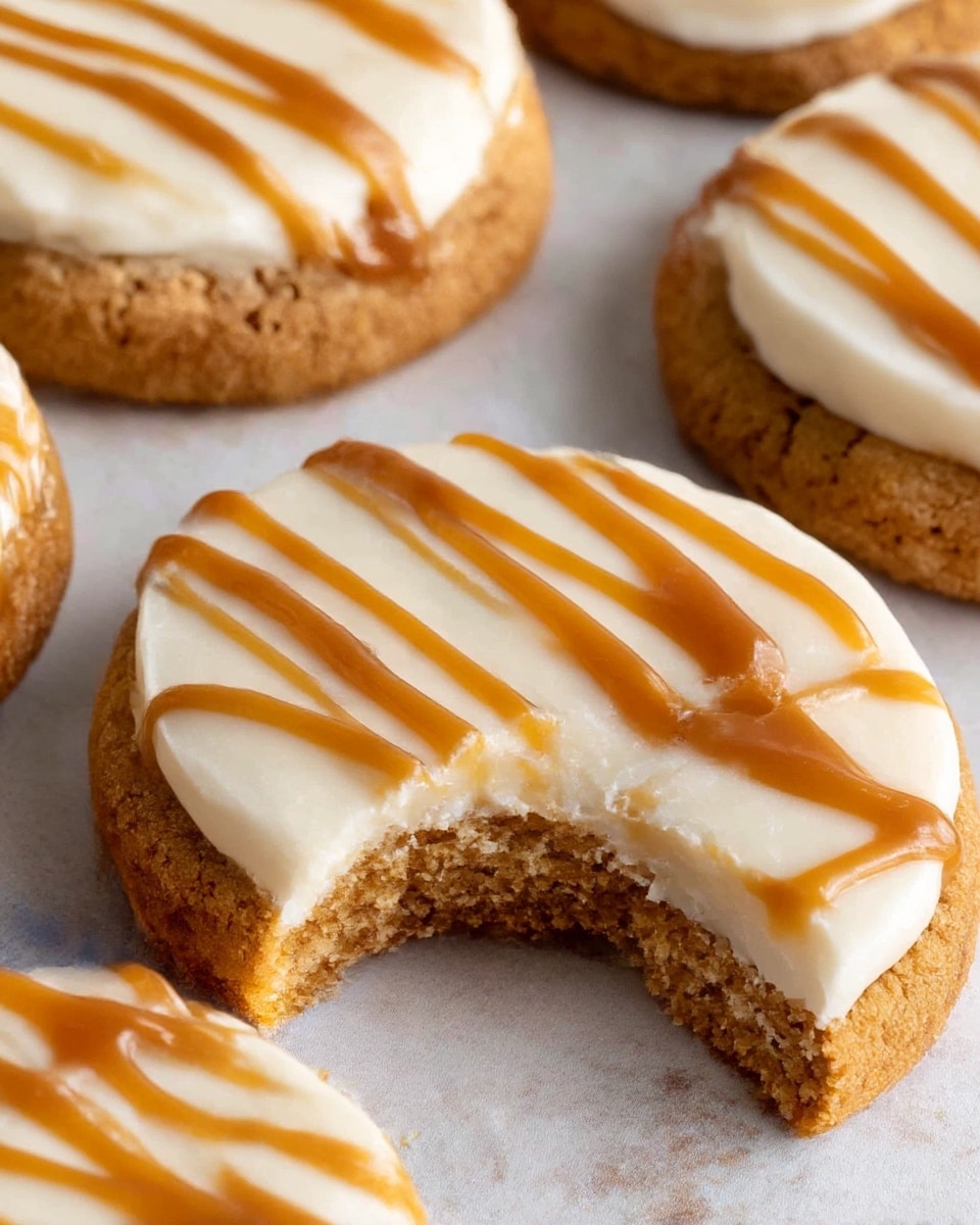 The image shows four round cookies placed closely together on a white marbled texture. Each cookie has a thick, golden-brown crumbly base, topped with a smooth, creamy white frosting layer. On top of the frosting, there are thin, wavy caramel-colored drizzle lines running across each cookie in a uniform pattern. One cookie in the center has a bite taken out of it, showing the soft inside of the cookie beneath the frosting and drizzle. photo taken with an iphone --ar 4:5 --v 7